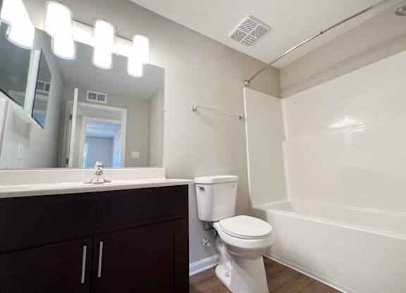 A white toilet sits next to a white bathtub in a bathroom.