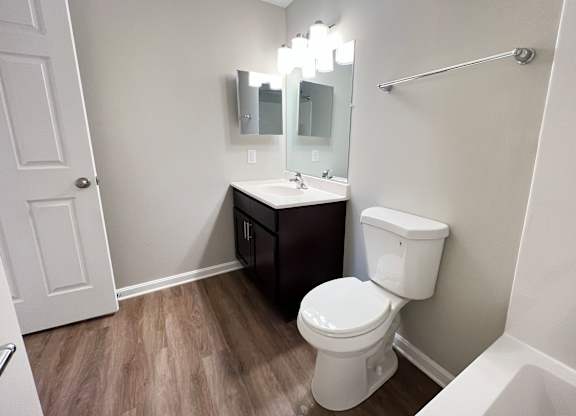 A white toilet sits in a bathroom with a sink and mirror.