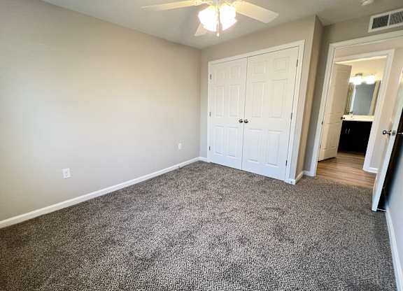 A room with a carpeted floor and a ceiling fan.