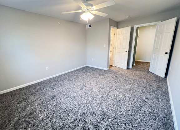 A room with a ceiling fan and carpeted floor.