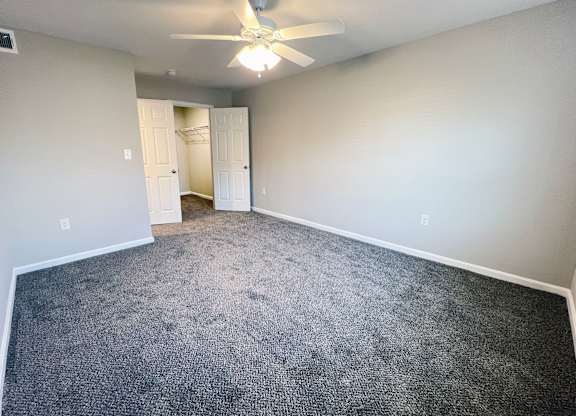 A room with a ceiling fan and carpeted floor.