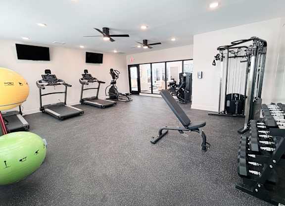 A spacious gym with a variety of equipment including treadmills, elliptical machines, and weight machines.