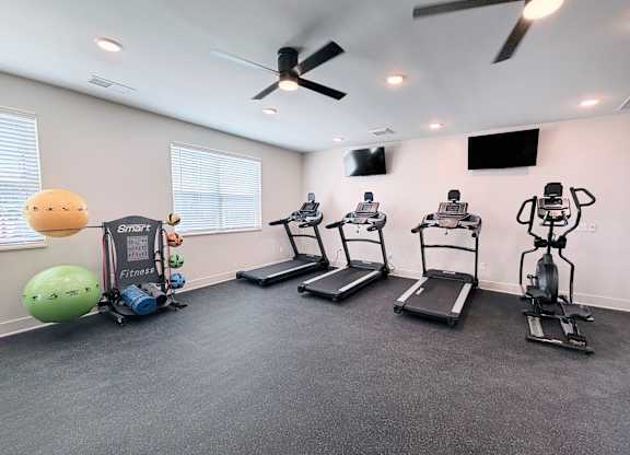 A room with a treadmill, exercise bike, and a ball.
