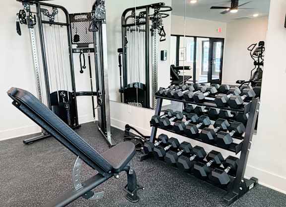 A gym with a bench, weights, and a mirror.