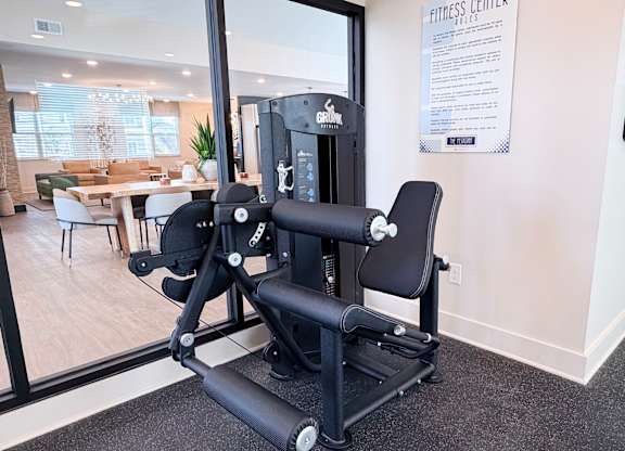 A gym room with a rowing machine and a sign on the wall.