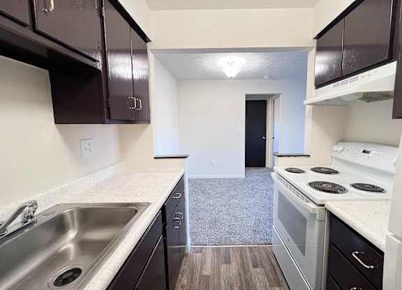 A kitchen with black cabinets and white appliances.