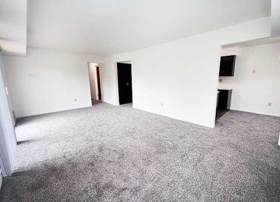 A large, empty room with carpeted flooring and white walls.