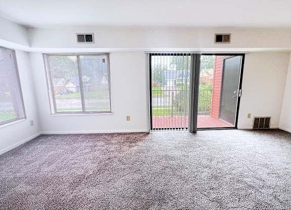 A room with a carpeted floor and a sliding glass door.