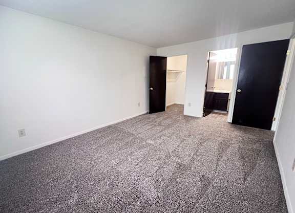 A room with a carpeted floor and two doors.