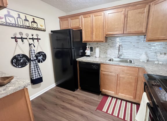 a kitchen with black appliances and wooden cabinets at Fox Run Apartments, Cincinnati