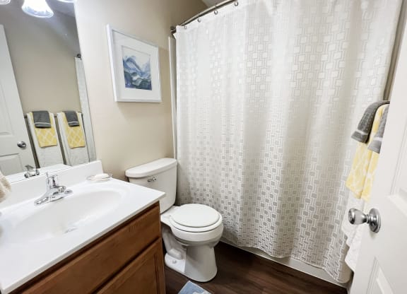 a bathroom with a white shower curtain and a toilet and sink at Fox Run Apartments, Cincinnati