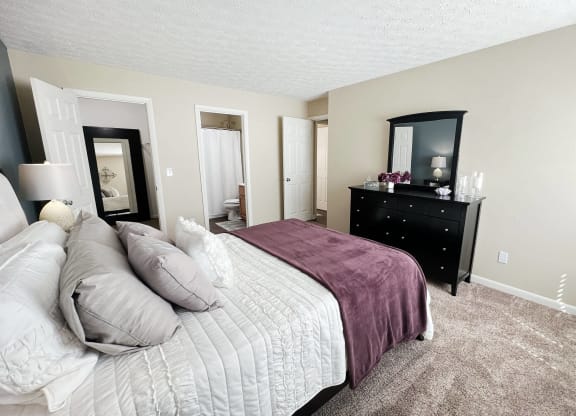 a bedroom with a bed and a dresser and a mirror at Fox Run Apartments, Cincinnati
