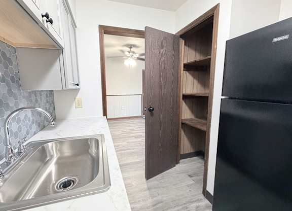 A kitchen with a black refrigerator and a sink with a silver faucet.