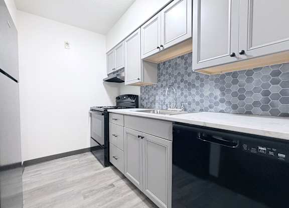 A kitchen with black appliances and white cabinets.