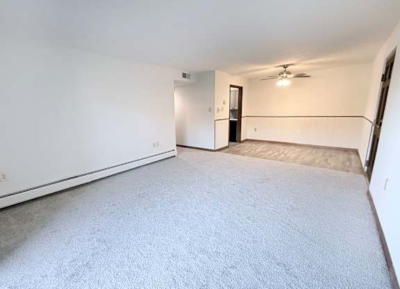 A spacious room with a carpeted floor and a ceiling fan.