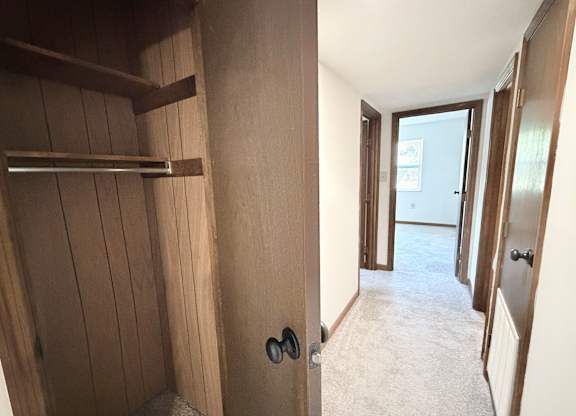 A hallway with a door on the right and a shelf on the left.