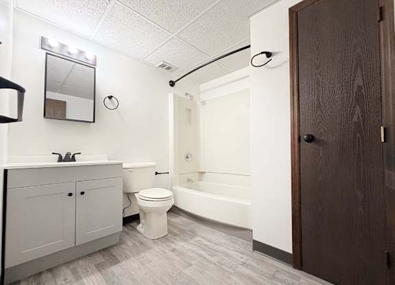 A white toilet sits in a bathroom next to a bathtub.