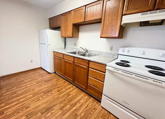 A kitchen with a white stove and wooden cabinets.