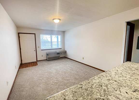A bedroom with a bed, dresser, and window.