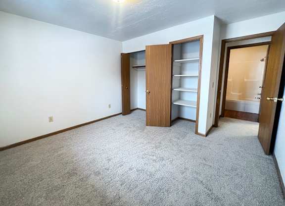 A room with a carpeted floor and a wooden door.