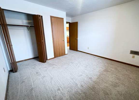 A room with a carpeted floor and two wooden doors.