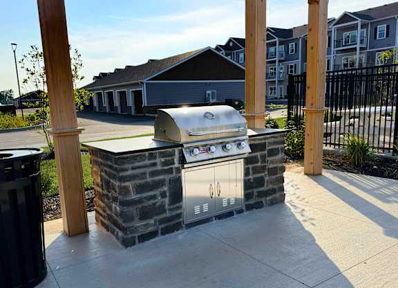 A BBQ grill is built into a stone structure in a residential area.