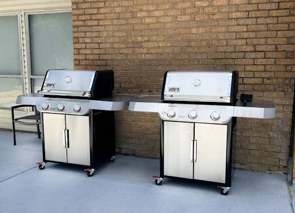 Two gas grills are on a patio.