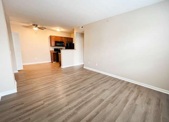 an empty living room with wood flooring and a kitchen at The Residences at Liberty Crossing, Columbus, OH, 43235