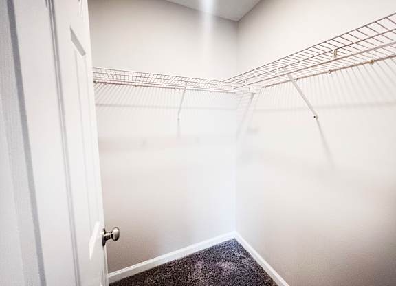 A white door is open to a hallway with a metal rack on the wall.