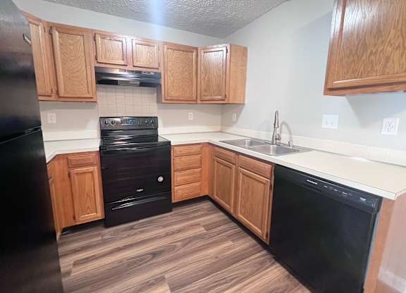 A kitchen with black appliances and wooden cabinets.