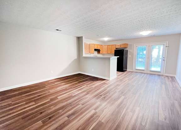 A room with wooden flooring and a black refrigerator.