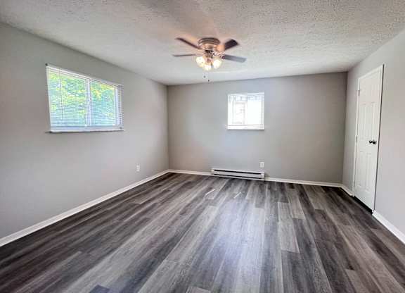 A room with a ceiling fan and wooden flooring.