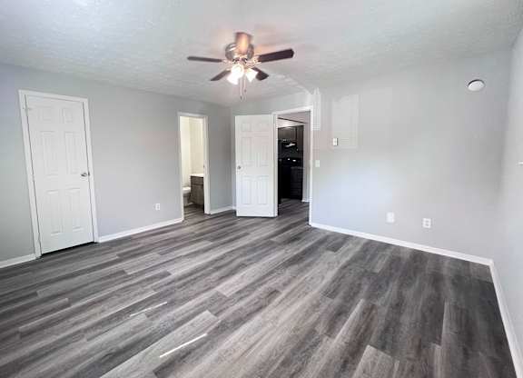 A room with a ceiling fan and wood flooring.