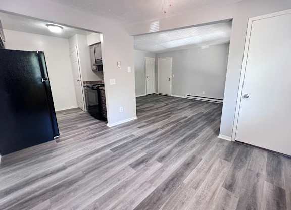 A kitchen area with a black fridge and a grey floor.