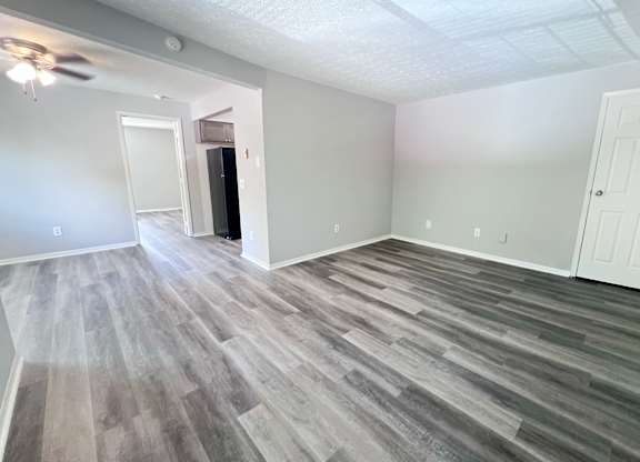 A room with a ceiling fan and wood flooring.