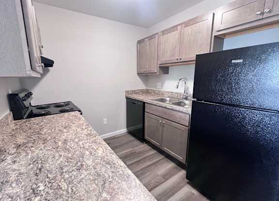 A kitchen with a black refrigerator and granite countertop.