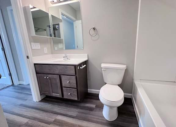 A white toilet sits in a bathroom next to a sink and a bathtub.