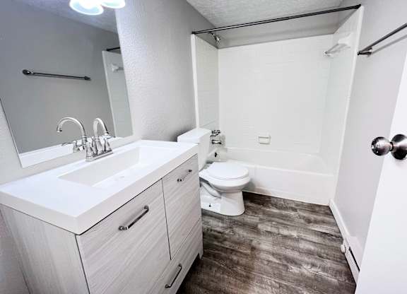 A white bathroom with a toilet, sink, and mirror.
