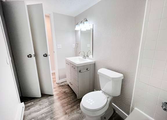 A white toilet in a bathroom with a white cabinet and a white sink.