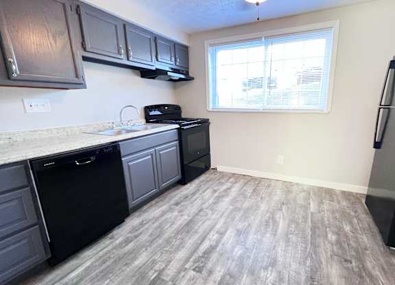 A kitchen with black appliances and grey cabinets.