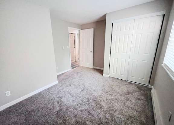 A room with a carpeted floor and two doors.