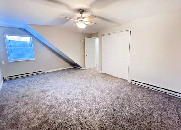 A room with a ceiling fan and carpeted floor.