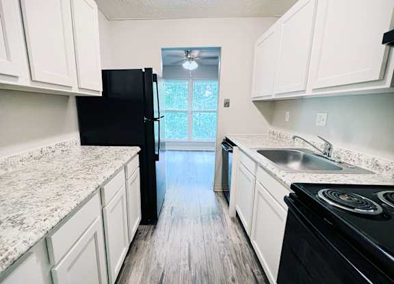 A kitchen with black appliances and white cabinets.