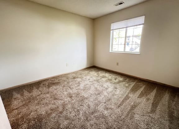 an empty bedroom with carpet and a window at Eagle Crest Apartments, Ohio, 43119