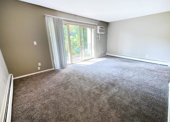 an empty living room with carpet and a sliding glass door  at Crown Pointe Apartments, Kentucky, 41014