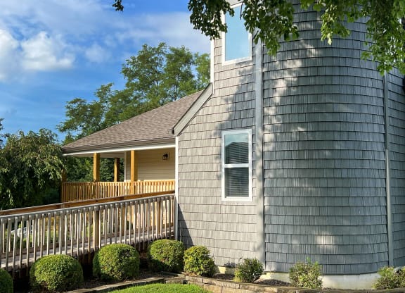 a gray house with a porch and a gray shingle roof at 450 on Keeneland Apartments, Richmond, 40475