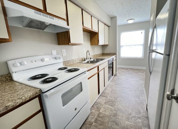 an empty kitchen with white appliances and granite counter tops at 450 on Keeneland Apartments, Richmond