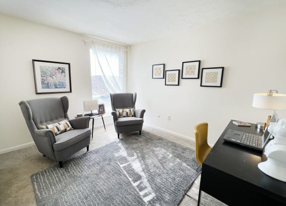 a living room with two chairs and a desk with a laptop