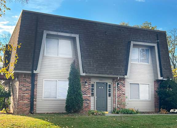 a brick house with a green door and a lawn