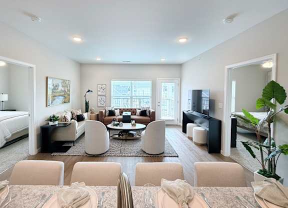 A well-lit, modern living room with a dining area in the foreground.